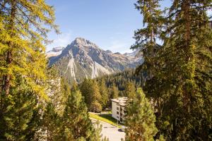 einen Berg in der Ferne mit einem Gebäude und Bäumen in der Unterkunft Miraflor Betty by Arosa Holiday in Arosa