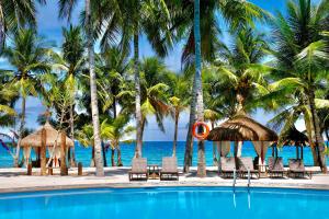 a swimming pool with palm trees and the ocean at Coco Grove Beach Resort, Siquijor Island in Siquijor