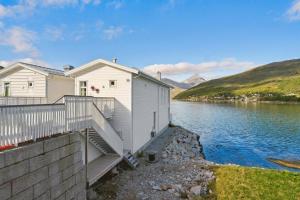a white house with stairs next to a body of water at Studio Seaside in Tromsø +8 photos