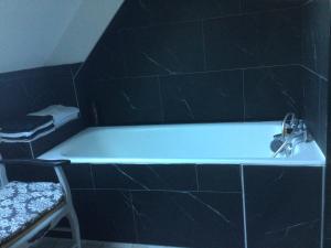 eine Badewanne mit einem Wasserhahn im schwarzen Bad in der Unterkunft L’hirondelle du Faubourg 