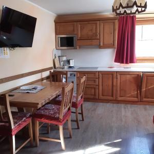 a kitchen with wooden cabinets and a wooden table with chairs at Bait DossAlt in Livigno