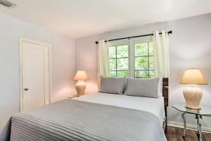 a white bedroom with a bed and two lamps at Vibrant West Palm Beach Home Less Than 2 Mi to Beach! in West Palm Beach