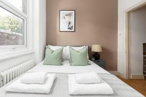 a bedroom with a bed with green pillows and a window at The Goldhawk Road Apartments in London
