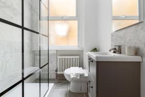 a bathroom with a toilet and a sink and a window at The Goldhawk Road Apartments in London