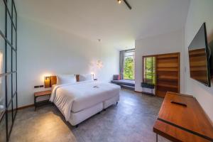 una camera con letto bianco e tavolo in legno di Baan Ploy Sea a Ko Samed