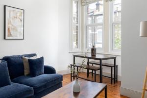 a living room with a blue couch and a table at The Goldhawk Road Apartments in London