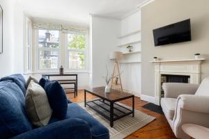 The Goldhawk Road Apartments في لندن: غرفة معيشة مع أريكة زرقاء ومدفأة