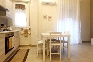 a kitchen with a white table and chairs and a window at Nichila - Casa Vacanze acitrezza in Acitrezza