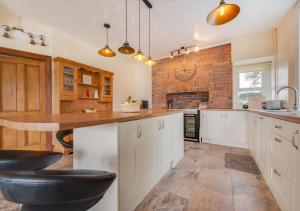 a kitchen with white cabinets and a brick wall at Greengrove Farmhouse Glasallt in Llangadog