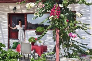 una mujer parada en una ventana con una mesa y flores en Lydia House by Elefthia Syros, en Megas Gialos - Nites