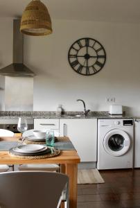 a kitchen with a washing machine and a clock on the wall at Altos de Baiona in Baiona