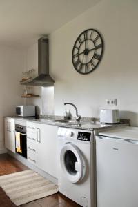 a kitchen with a washing machine and a clock on the wall at Altos de Baiona in Baiona