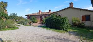 a house with a gravel road in front of it at Le Corolle in Montepulciano
