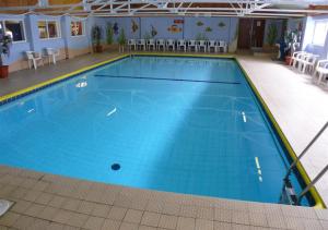 a large swimming pool with blue water in a building at Gowerhaven in Knelston