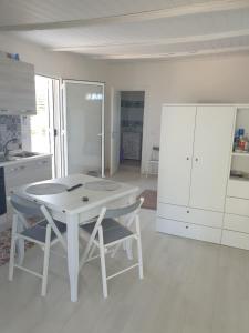 a white kitchen with a white table and chairs at CASA DEL SOLE in Alcamo +8 photos