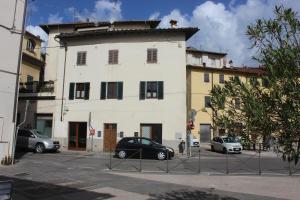 a white building with cars parked in front of it at San Bartolomeo Apartment in Pistoia