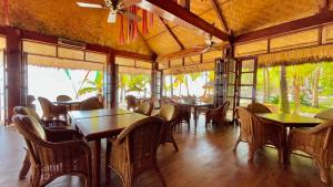una sala da pranzo con tavoli, sedie e finestre di Coco Grove Beach Resort, Siquijor Island a Siquijor