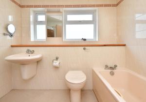 uma casa de banho com um WC, um lavatório e uma banheira em Gerddi em Llanbedrog