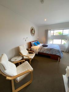 a bedroom with a bed and chairs and a window at Serenity Lodge for Couples in Ulladulla