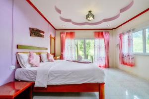 a bedroom with a large bed with pink curtains at Ingthara Resort in Phangnga