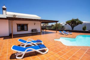 un patio con tumbonas y una piscina en Casa Lola Lanzarote piscina climatizada y wifi free, en San Bartolomé