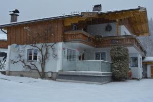 une maison avec de la neige devant elle dans l'établissement Gästehaus Huber, à Leogang