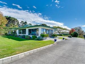 a house on a street with a green lawn at Tango10 Accommodation - Best views in Hawke's Bay in Tangoio