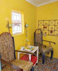 a yellow room with two chairs and a table at Malan's Rust in Sutherland