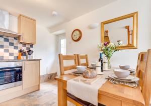 a kitchen and dining room with a table and a mirror at Pigsty Cottage in Knelston