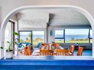 a dining room with a table and chairs and the ocean at Tango10 Accommodation - Best views in Hawke's Bay in Tangoio