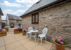 a patio with two chairs and a table at Pigsty Cottage in Knelston