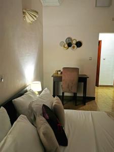 Un dormitorio con una cama blanca con almohadas y una mesa en L'Address en Cotonú