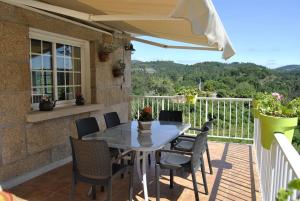 a table and chairs on a balcony with an umbrella at Casa da Buxeira . Entorno magico. in Caritel