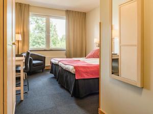 HörbyにあるRingsjöstrand Hotelのベッド、デスク、窓が備わるホテルルームです。