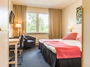 a hotel room with a bed and a desk and a window at Ringsjöstrand Camping, Hotell och Stugby in Hörby