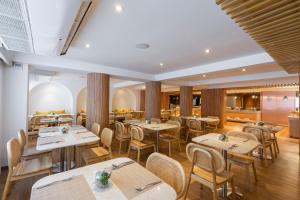 a restaurant with tables and chairs in a room at Arck Hotel in Bangkok
