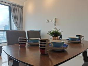 una mesa de comedor con tazas y tazones. en SKS Pavillion 1Bedroom High Floor @2pax By HAUZ CINTA, en Johor Bahru