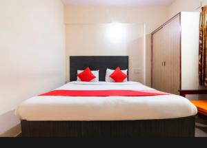 um quarto com uma cama grande e almofadas vermelhas em Royal Guest Inn HSR Layout em Bangalore