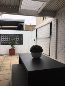 een zwarte tafel met een potplant op een patio bij Modern Central China town Home - Free Carpark in Adelaide