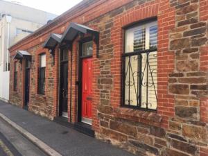 a brick building with a red door on a street at Modern Central China town Home - Free Carpark in Adelaide