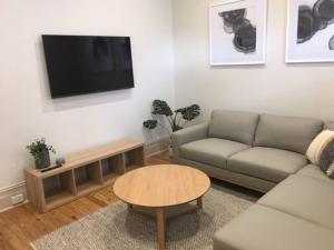 uma sala de estar com um sofá, uma mesa e uma televisão em Modern Central China town Home - Free Carpark em Adelaide