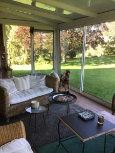 a living room with a couch and tables and windows at L’hirondelle du Faubourg in Saudemont