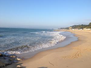 a beach with the ocean and people walking on it at Grovefield Manor in Poole