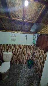 a bathroom with a toilet and a light on the ceiling at Kampung Bareto Cottage And Resto in Tjisurupan