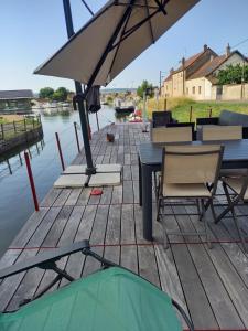 een steiger met een tafel en stoelen en een paraplu bij LES AMIS D'ULYSSE in Chagny