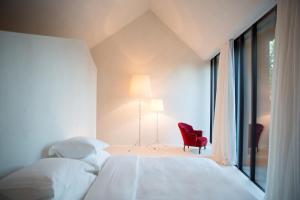 RegensbergにあるHotel Krone Regensbergのベッドルーム1室(ベッド2台、赤い椅子、窓付)