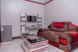 a living room with a couch and a tv at Yobo's Complex Guest House in Kampala