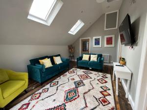 a living room with two blue couches and a rug at Lime Tree Cottage in Tillingham