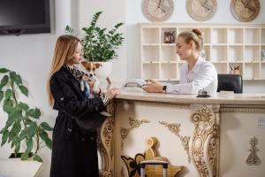 een vrouw die voor een toonbank staat en met een vrouw praat bij Курортний Готель Золота Корона in Truskavets