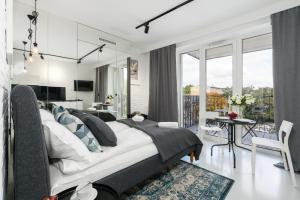 a bedroom with a large bed and a balcony at Apartments Poznań MTP Bukowska by Renters in Poznań